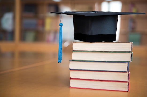 Black graduated cap and blue tassel placed on the book.