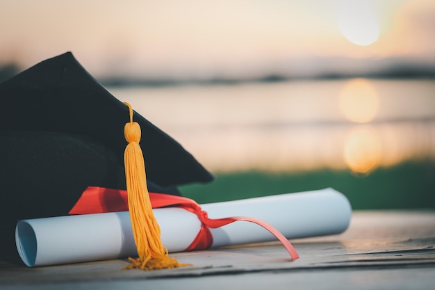 Foto un berretto graduato nero e un certificato posto su una scrivania in legno