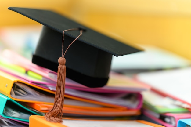 Black graduation cap placed on a file folder on a desk