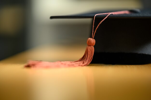 Black graduation cap placed on a wooden table