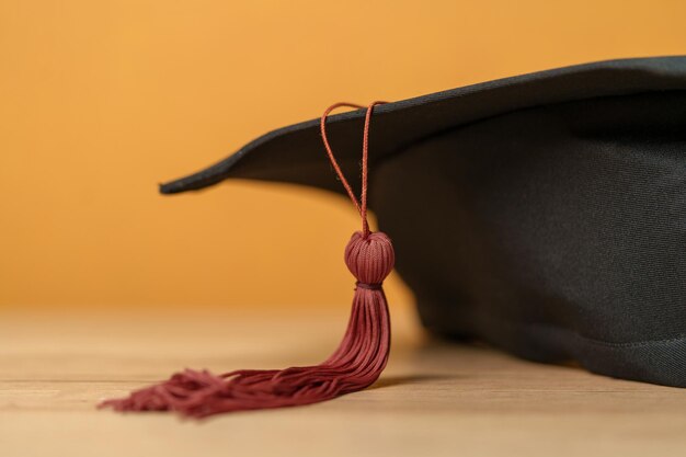 Black graduation hat placed on wood desk background