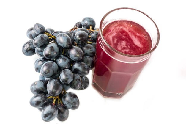 Black grapes glass of grape juice white background