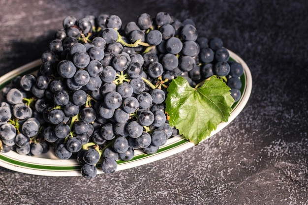 Black grapes lie on a white plate with an oval green stripe