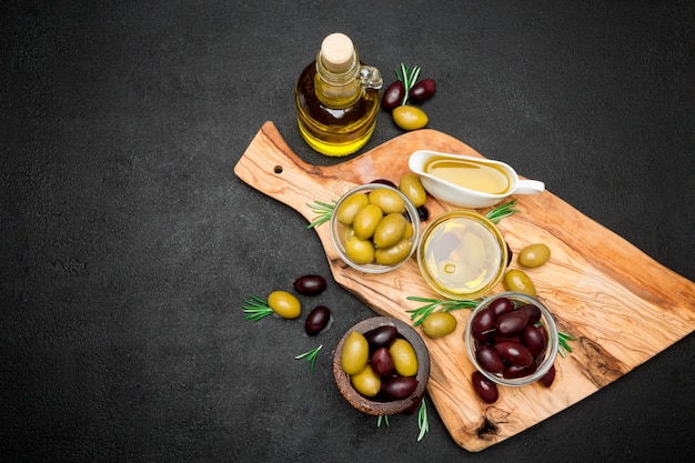 Black and green olives and oil on wooden cutting board