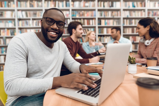 Ragazzo nero sul portatile nella biblioteca della scuola.