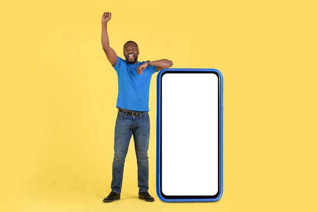 Black Guy Leaning On Huge Cellphone Shaking Fist Yellow Background