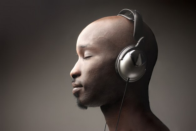 Черный парень в профиле слушает музыку в наушниках