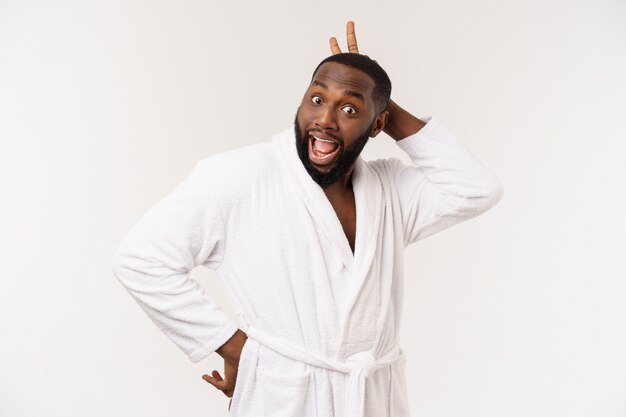 Black guy wearing a bathrobe pointing finger with surprise and happy emotion. Isolated.
