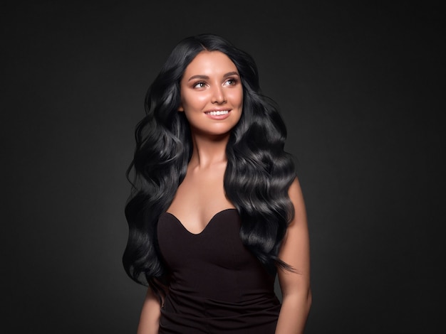 Black hair woman long curly beauty cosmetic concept over black background. Studio shot.