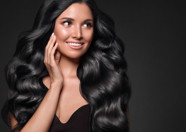 Black hair woman long curly beauty cosmetic concept over black background. Studio shot.