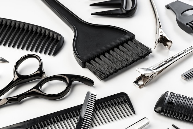 Черные парикмахерские инструменты и различные щетки для волос на белом фоне