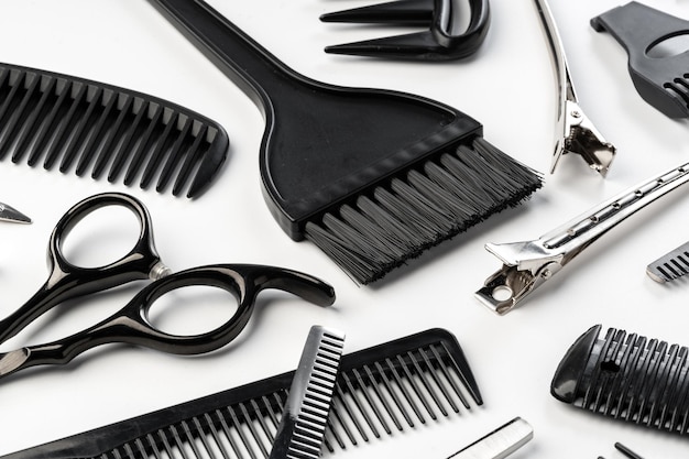 Black hairdressing tools and various hairbrushes on white background