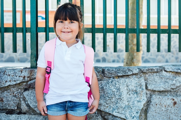 写真 ピンクのバックパックを身に着けている黒髪の女の子は学校に行きます