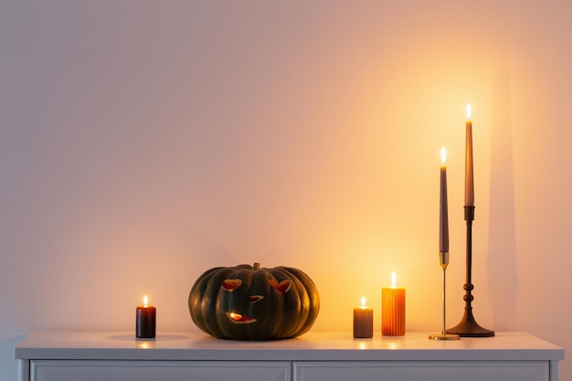 Черная тыква хэллоуина с горящими свечами в белом интерьере