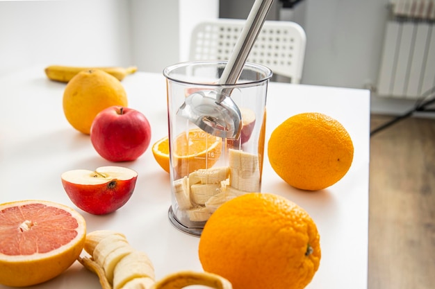 Black hand blender being used to make fresh fruit smoothie in the kitchen