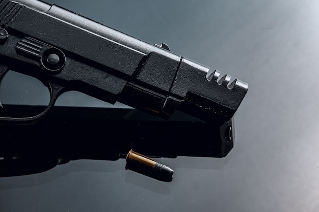 Black handgun on black background with reflection close up