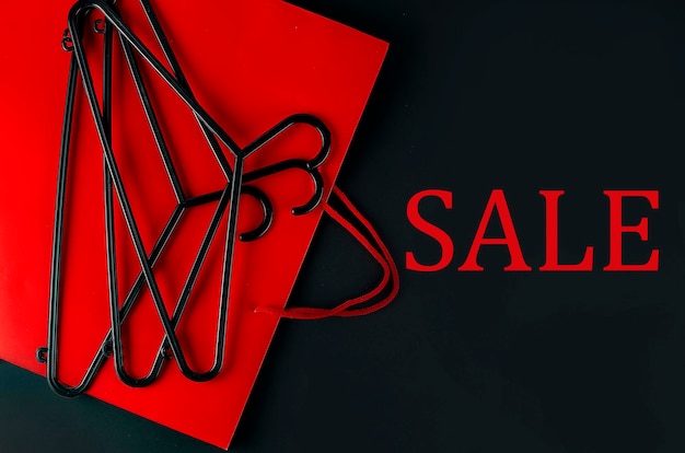 Photo black hanger and red bag on the black background. black friday sale concept. text sale