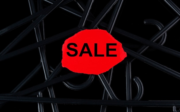 Photo black hangers and text sale on the tor paper on black background. discounts. seasonal sale.