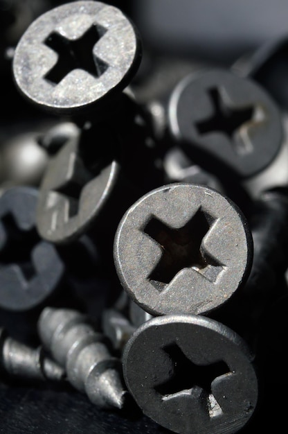 Photo black hardened self-tapping screws lies on a dark background. close-up.