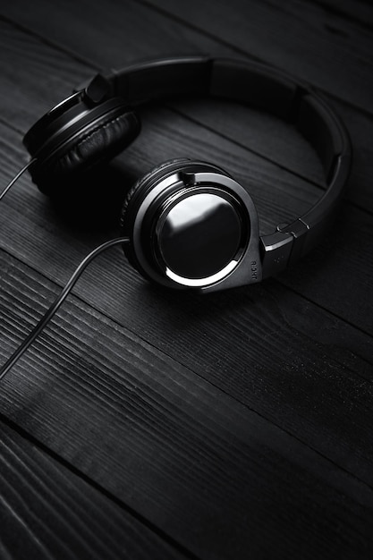 Black headphones on black wooden dark background