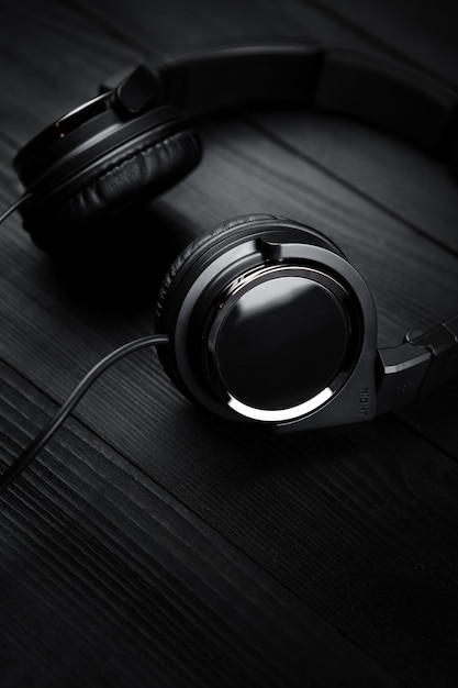 Photo black headphones on black wooden dark background