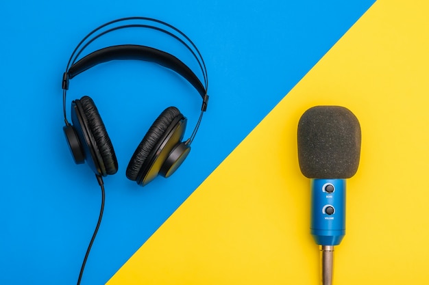 Black headphones and blue microphone on light yellow and blue.