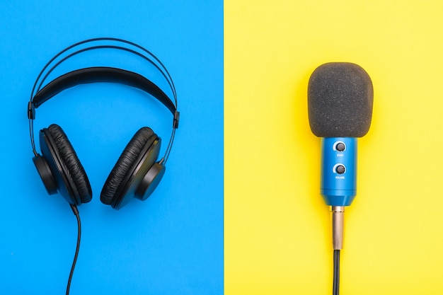 Black headphones and blue microphone on yellow and blue