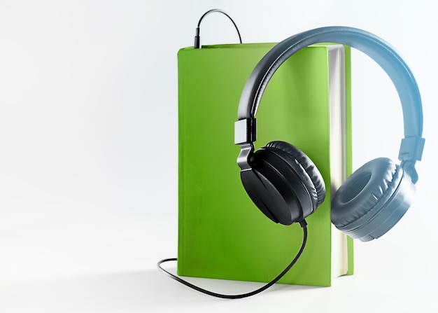 black headphones and a green book on a light background.