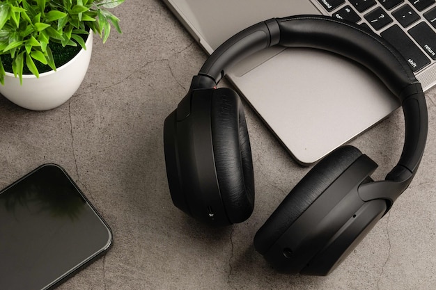 Black headphones on a grey table Concept of playing music with a smartphone and listening with wireless headphones in the living room and work at home Closeup selective focus Blurred background