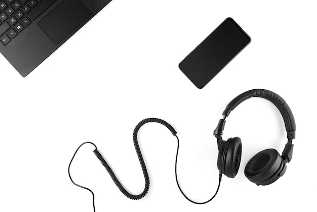 Black headphones, smartphone and laptop on a white background.