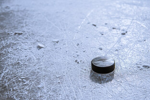 Black hockey puck lies on ice at stadium