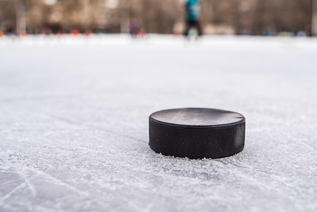 Black hockey puck lies on ice at stadium