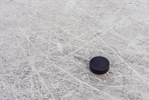 Photo black hockey puck lies on ice at stadium