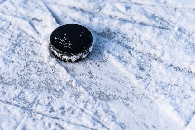 Photo black hockey puck lies on ice at stadium