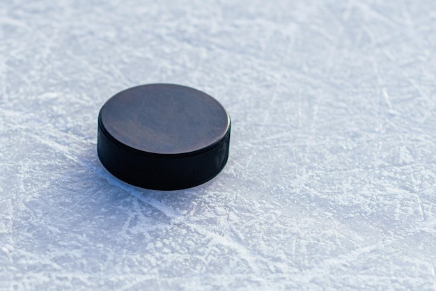 Black hockey puck lies on ice at stadium