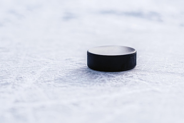 Black hockey puck lies on ice at stadium