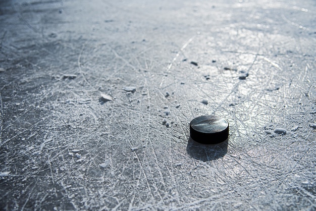 Black hockey puck lies on ice at stadium