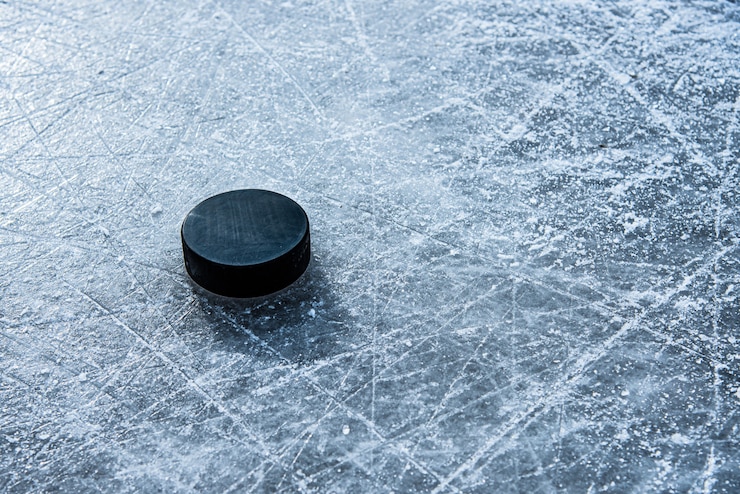 Photo black hockey puck lies on ice at stadium