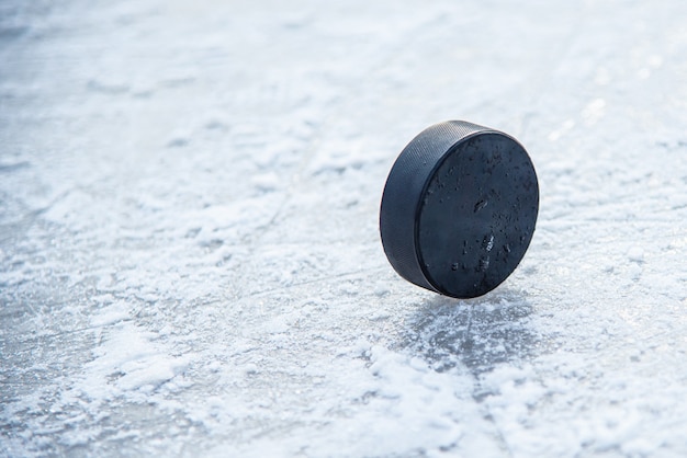 Фото Черная хоккейная шайба лежит на льду на стадионе