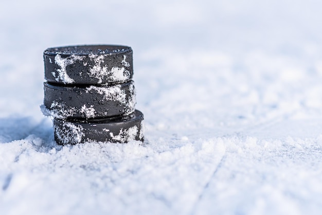 Черные хоккейные шайбы лежат на льду на стадионе