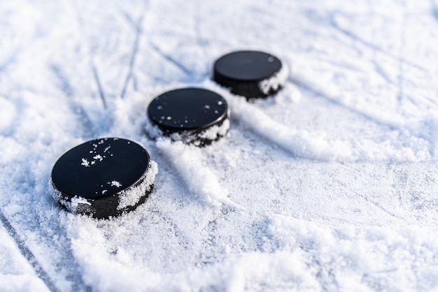 Black hockey pucks lies on ice at stadium