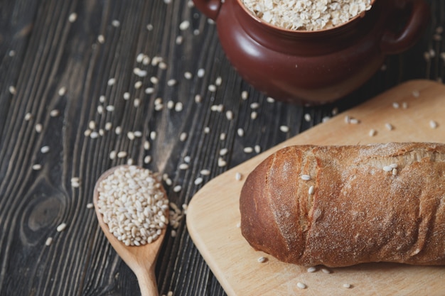 Black homemade bread and its ingredients on rustic table.