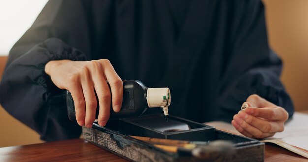 Black ink calligraphy or hands of Japanese artist in studio for art and script letter with closeup for alphabet Start ready or person with tools paintbrush and focus with traditional stationery