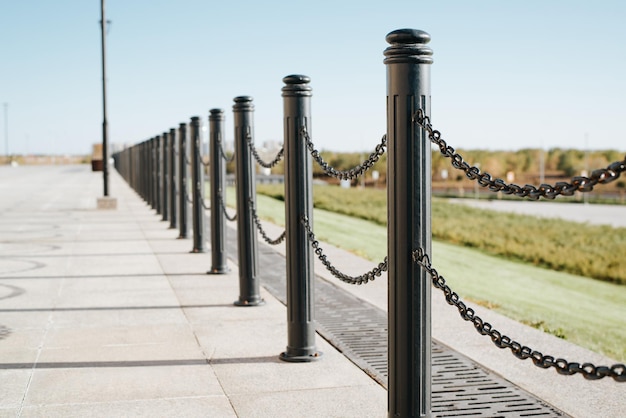 Black iron fence posts with chain Decorative fence pillar outdoors on a sunny day perspective view