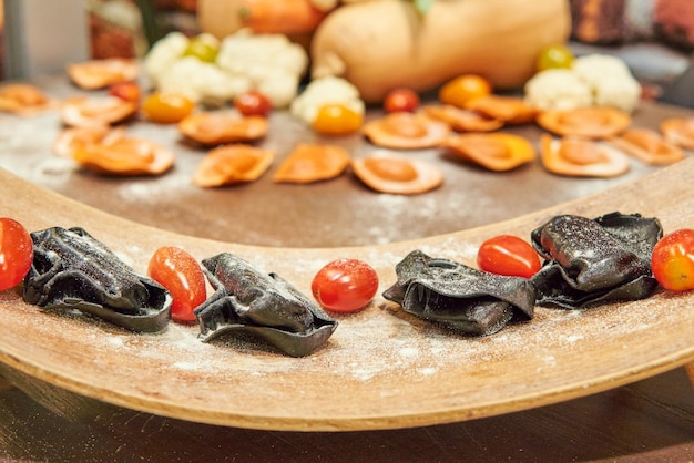 Photo black italian pasta on the front and orange pumpking pasta on the backgroung