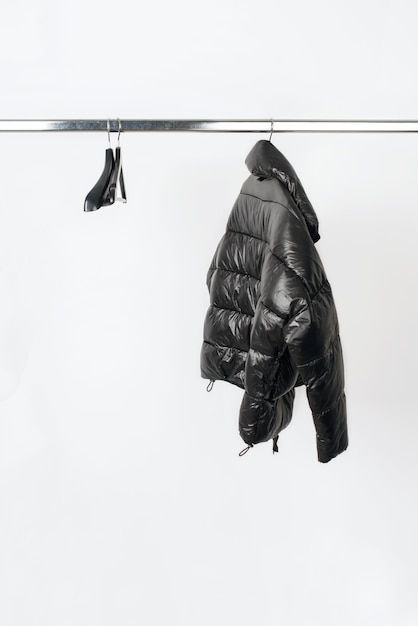Фото Черная куртка на вешалке, изолированные на белом фоне концепция минимальной модной одежды