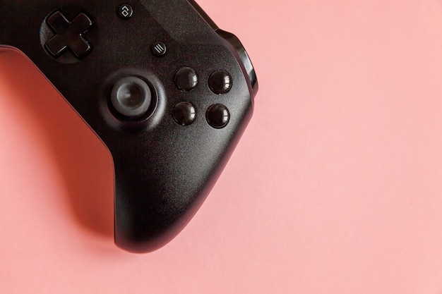 Black joystick gamepad, game console on pink colourful background