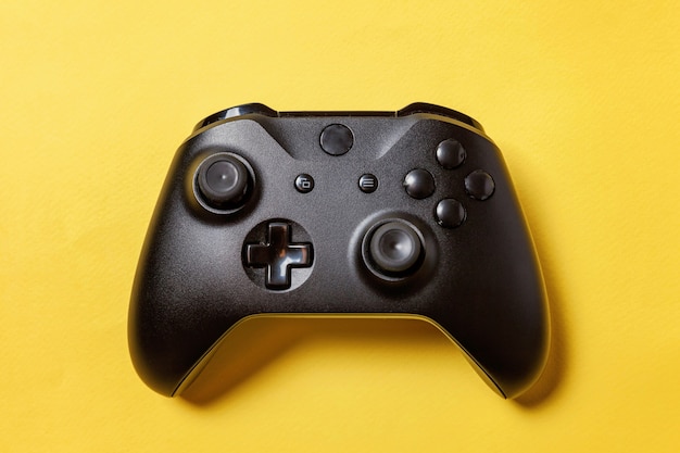 Black joystick gamepad, game console on yellow colourful background