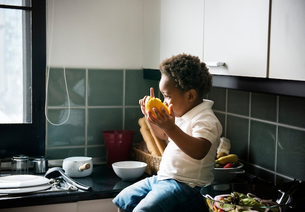 Photo black kid with orange in the kitchen