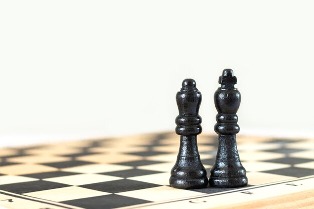 Black king and queen chess pieces on chess board close-up